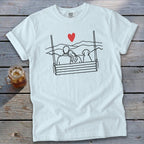 White t-shirt with black line art of couple and dog on swing, red heart above.