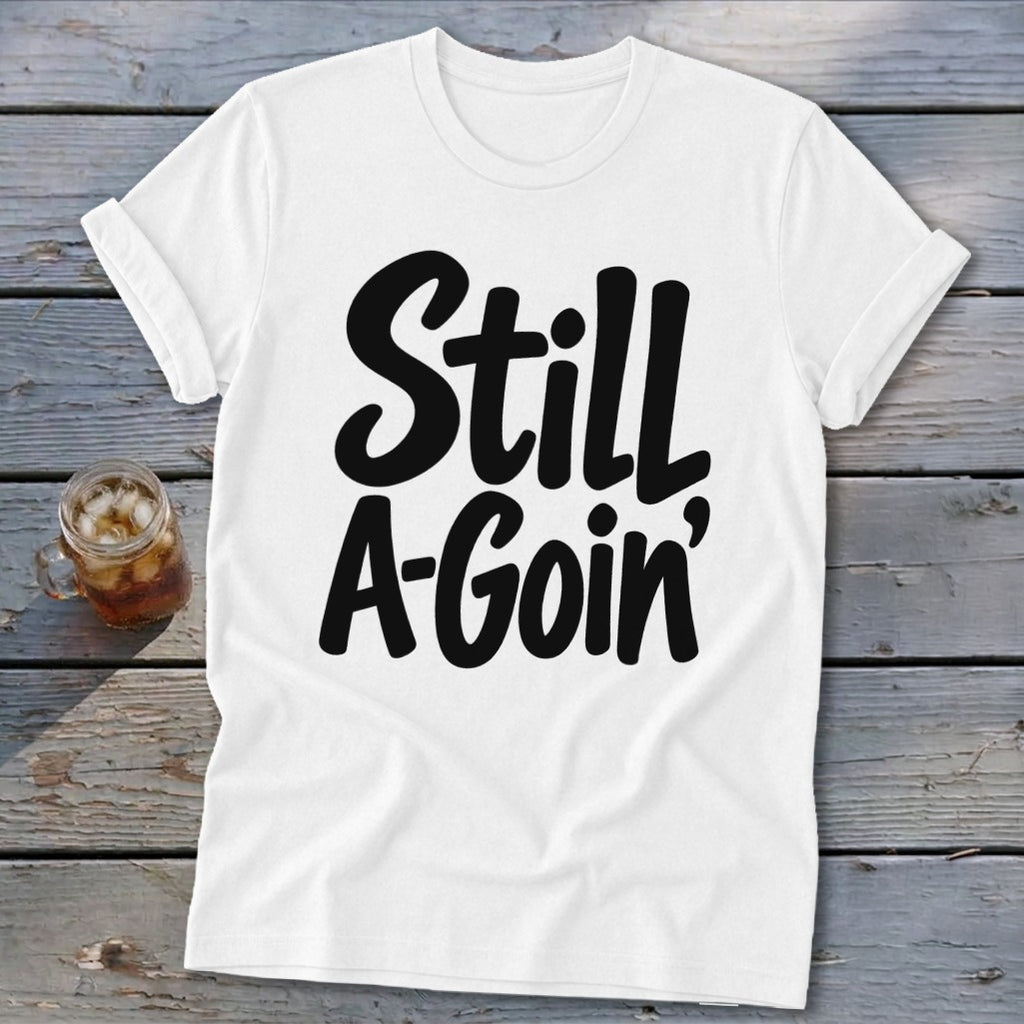 A white t-shirt with rolled sleeves features black text reading "Still A-Goin'".