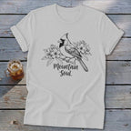 White t-shirt with a cardinal and flowers design and text "Mountain Soul".