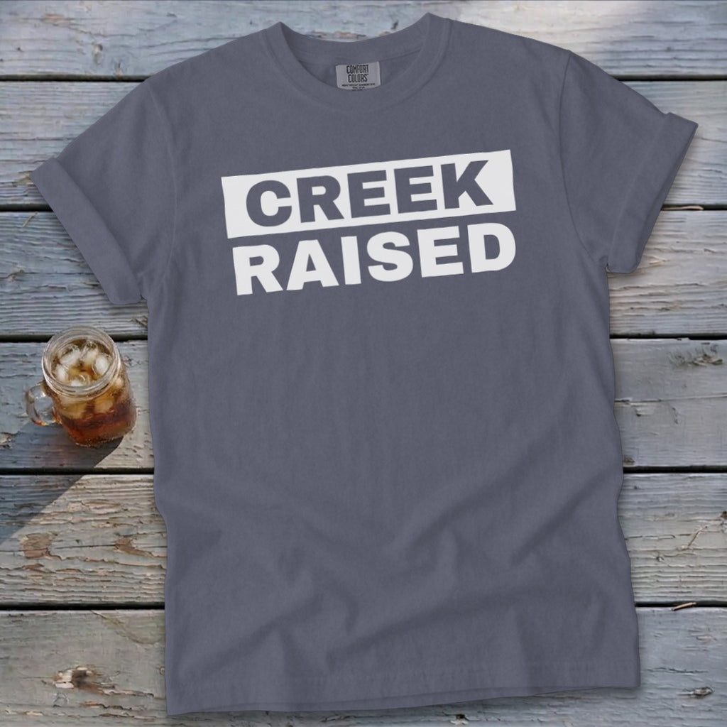 Grey t-shirt with white text that reads "CREEK RAISED".