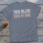 Grey t-shirt with white and peach text reading "THESE HOLLERS KNOW MY NAME".