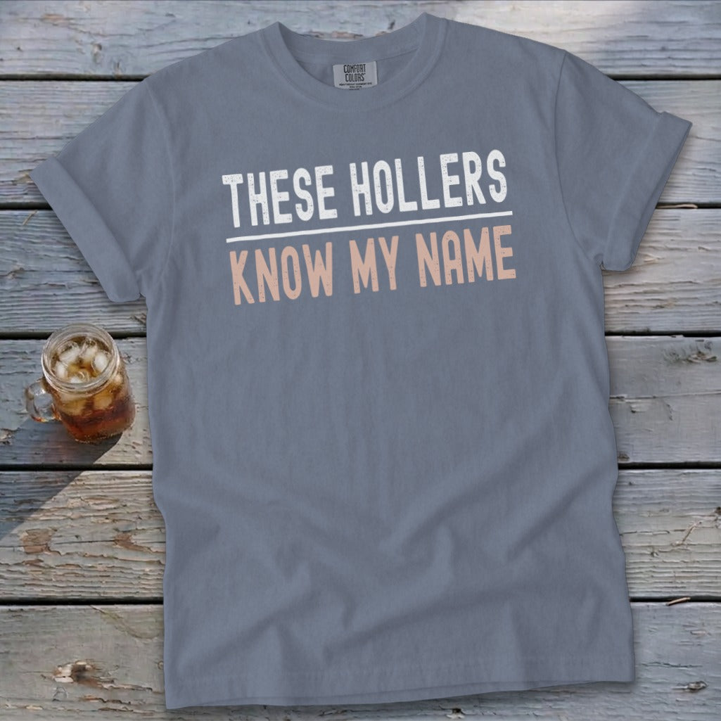 Grey t-shirt with white and peach text reading "THESE HOLLERS KNOW MY NAME".