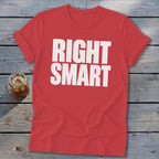 Red crewneck t-shirt with rolled sleeves, featuring the white block text RIGHT SMART, laid on a weathered wooden surface.