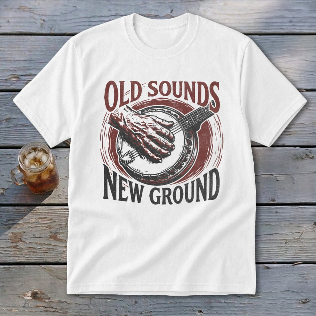 A white t-shirt featuring a graphic print of a hand playing a banjo and text that reads Old Sounds New Ground.