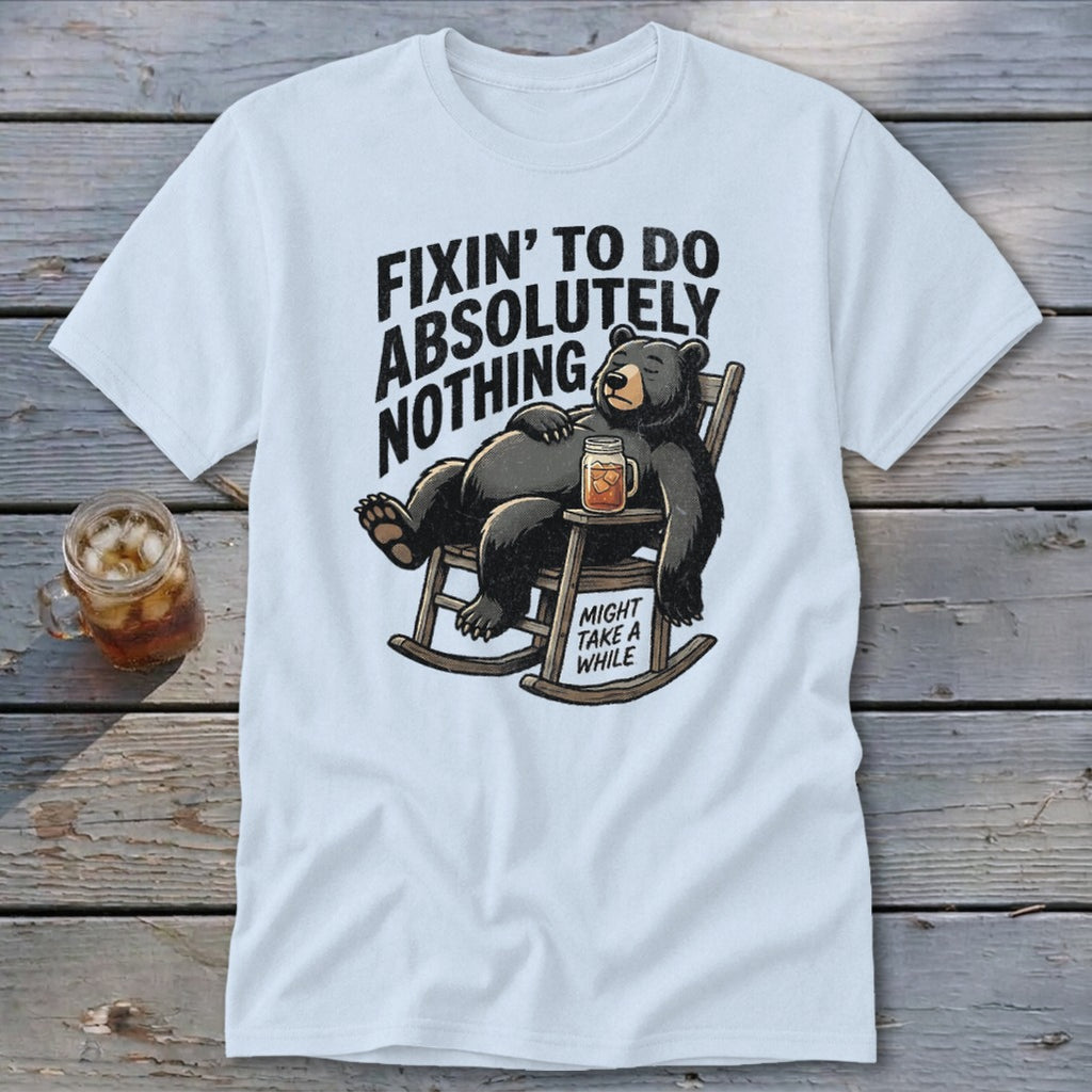 White t-shirt featuring a cartoon bear relaxing in a rocking chair with the text Fixin to Do Absolutely Nothing.