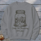 A grey crewneck sweatshirt featuring a graphic of a mountain landscape inside a glass jar, with text reading "Carry the Mountains with You."
