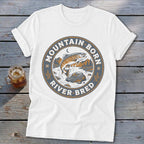 White t-shirt with a circular graphic of a jumping fish and text "MOUNTAIN BORN RIVER BRED".
