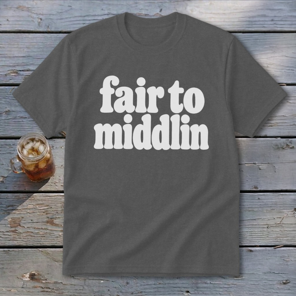 Gray t-shirt with white text "fair to middlin" on wooden background.
