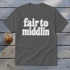Gray t-shirt with white text "fair to middlin" on wooden background.