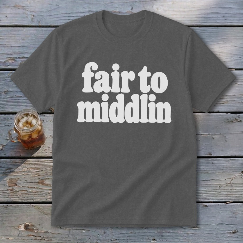 Gray t-shirt with white text "fair to middlin" on wooden background.