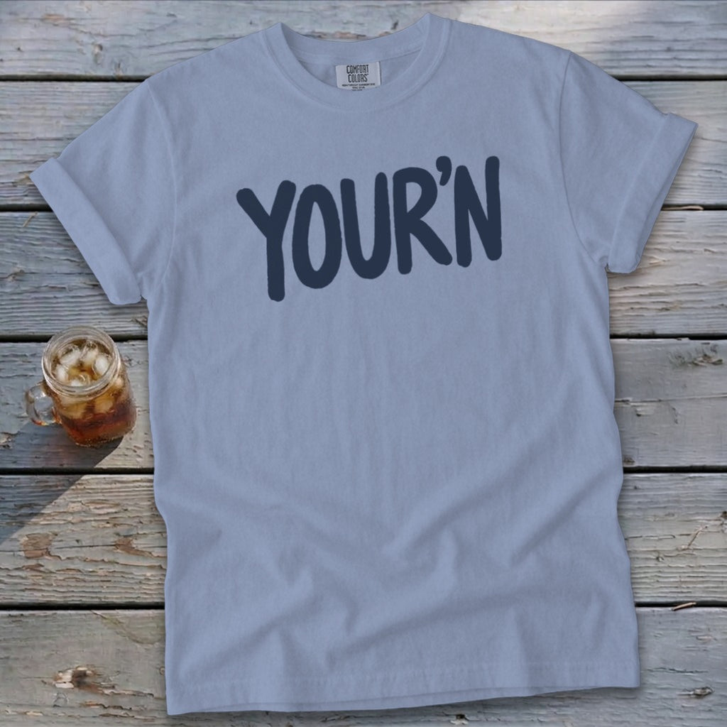 Light blue t-shirt with "YOUR'N" graphic and a glass of iced tea.