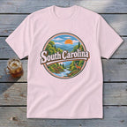 Pink t-shirt with circular South Carolina nature graphic featuring mountains, river, deer, and sun.