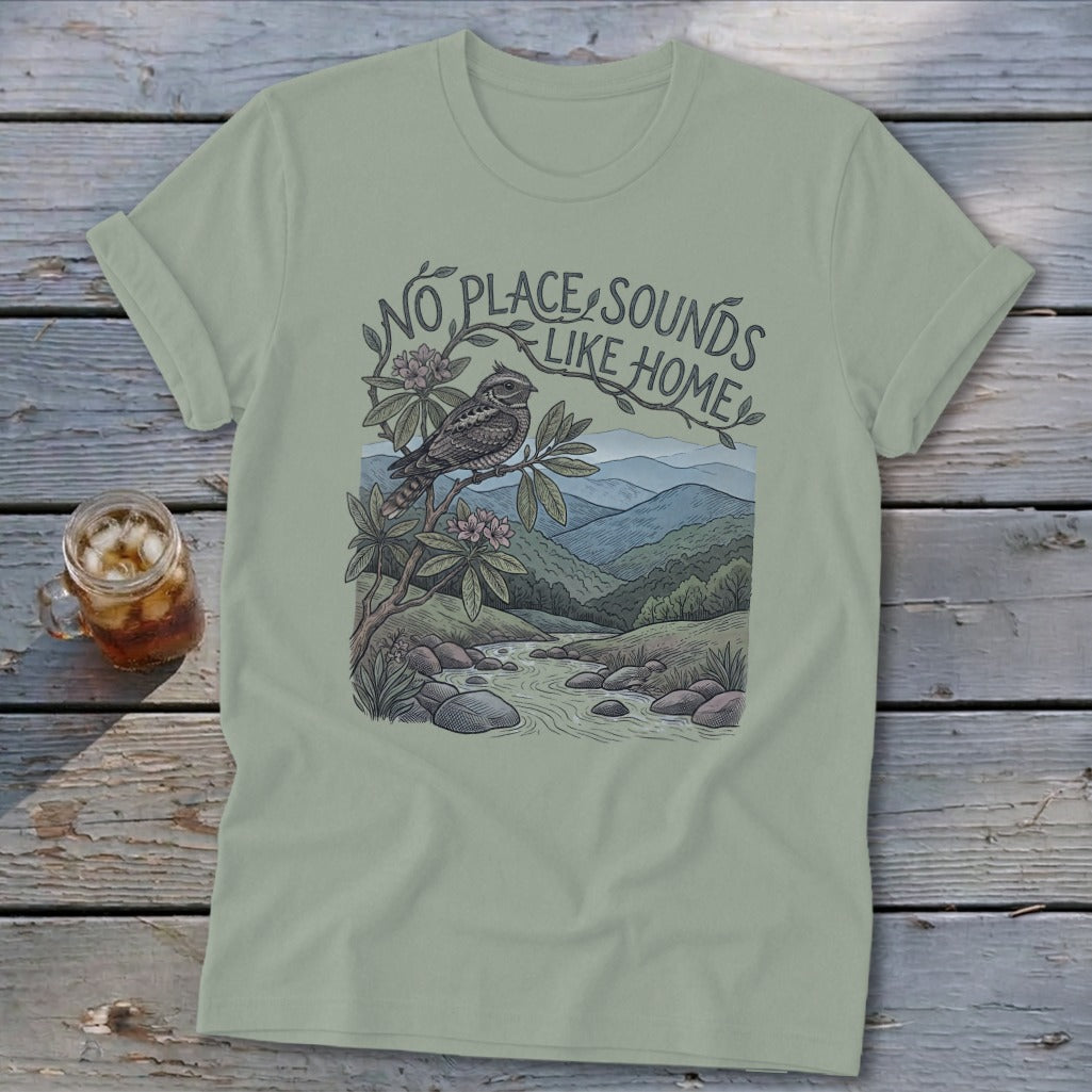 T-shirt graphic with bird on branch over a stream and mountains, reading "No Place Sounds Like Home."