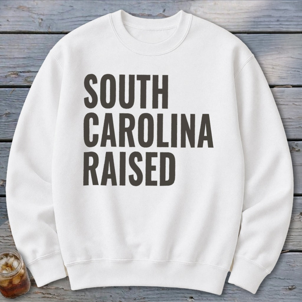 White crewneck sweatshirt with "SOUTH CAROLINA RAISED" printed in dark grey text.