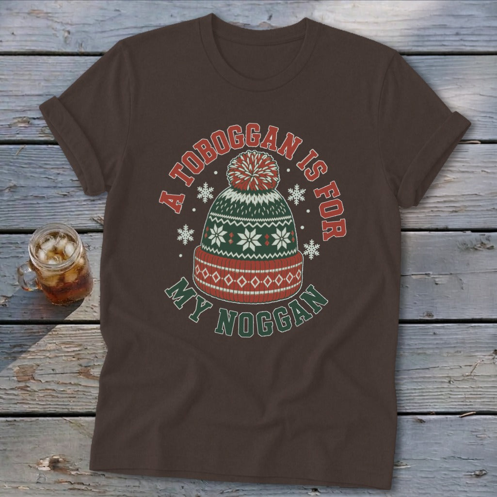 Brown t-shirt featuring a graphic of a winter hat with text reading A TOBOGGAN IS FOR MY NOGGAN.
