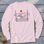 Couple and dog on a swing with heart and mountains graphic on a pink long-sleeve shirt.