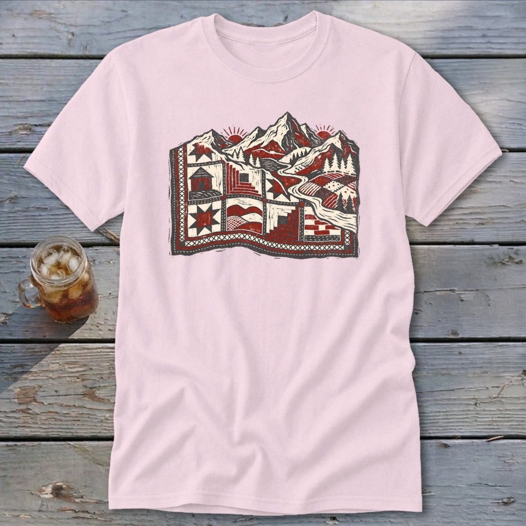 Light pink crewneck t-shirt featuring a red and black landscape quilt graphic on a wooden table.
