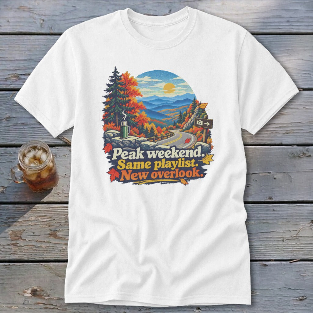 White t-shirt graphic with autumn mountain scene and text "Peak weekend. Same playlist. New overlook."