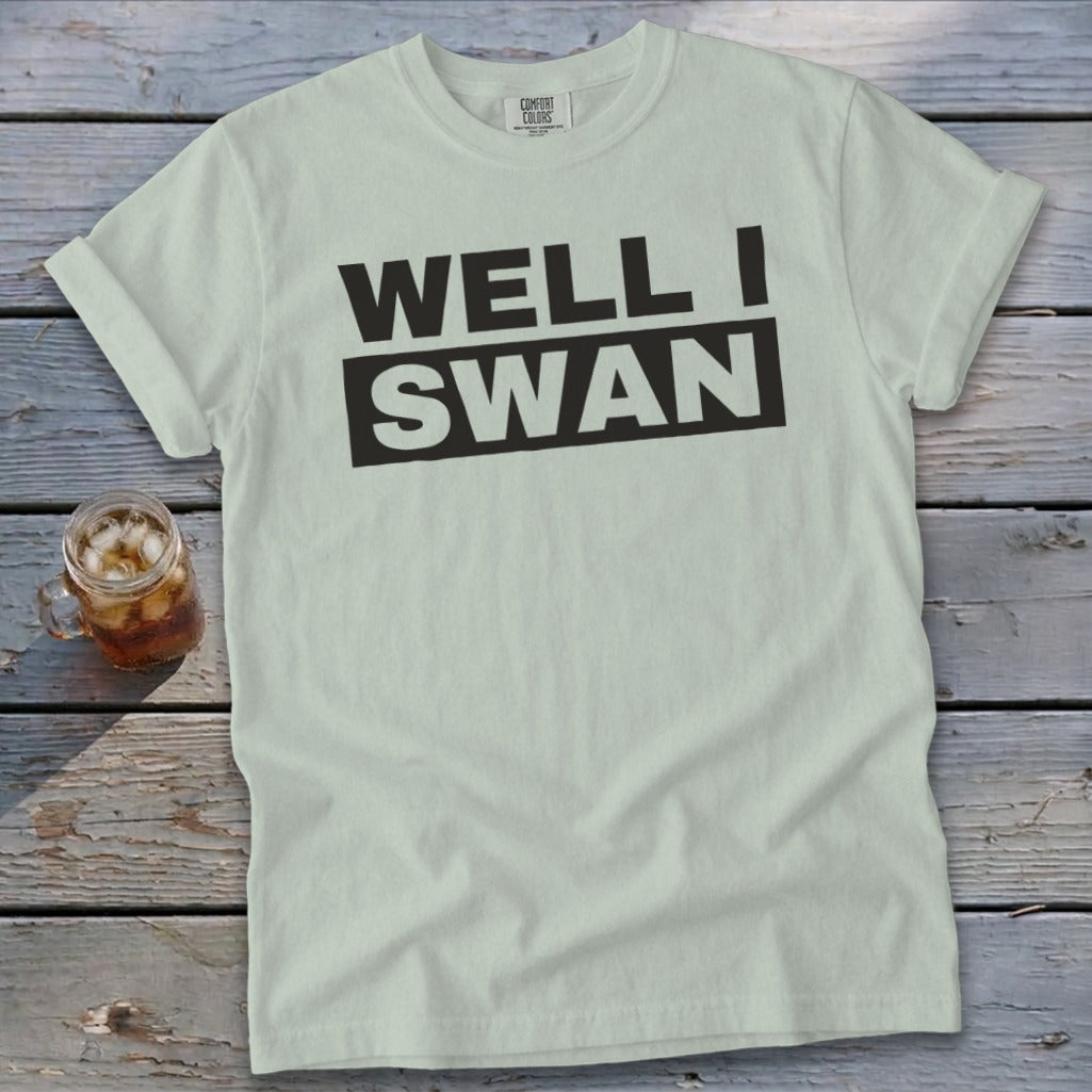 Light green t-shirt with rolled sleeves displaying black text that reads "WELL I SWAN".