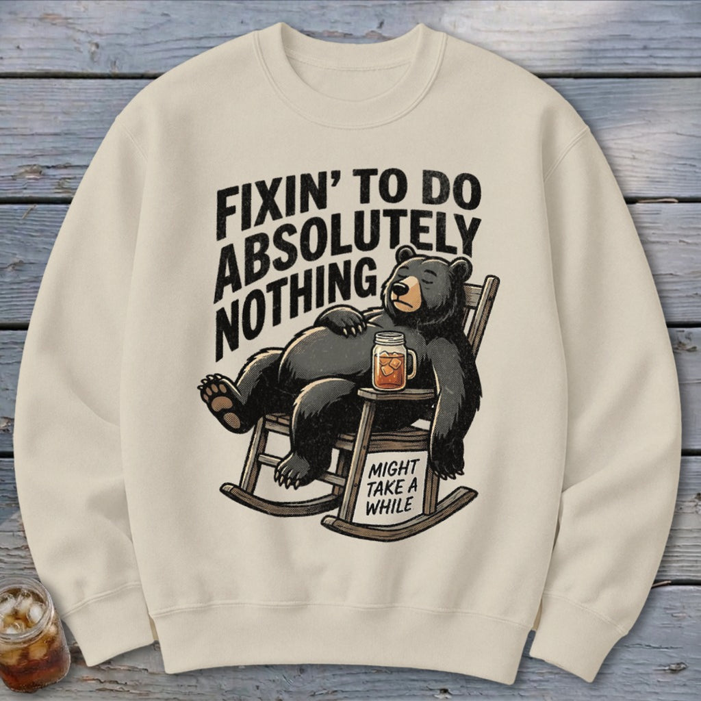 Beige crewneck sweatshirt with a graphic of a bear relaxing in a rocking chair, accompanied by text.