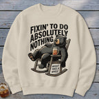 Beige crewneck sweatshirt with a graphic of a bear relaxing in a rocking chair, accompanied by text.