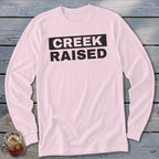 Pink long-sleeve shirt with "CREEK RAISED" text in black.