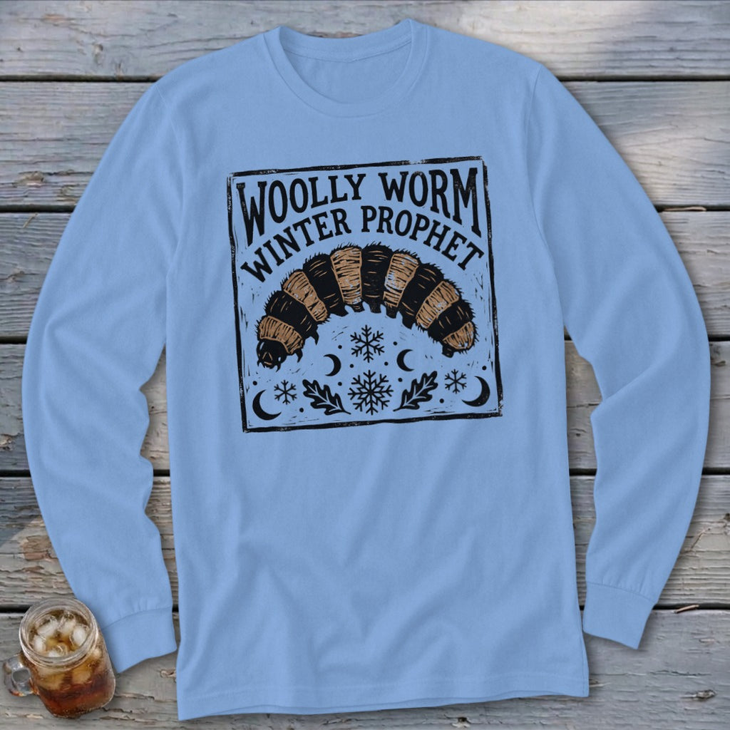 A light blue long-sleeve t-shirt features a black block-print graphic of a woolly worm and text reading Woolly Worm Winter Prophet.
