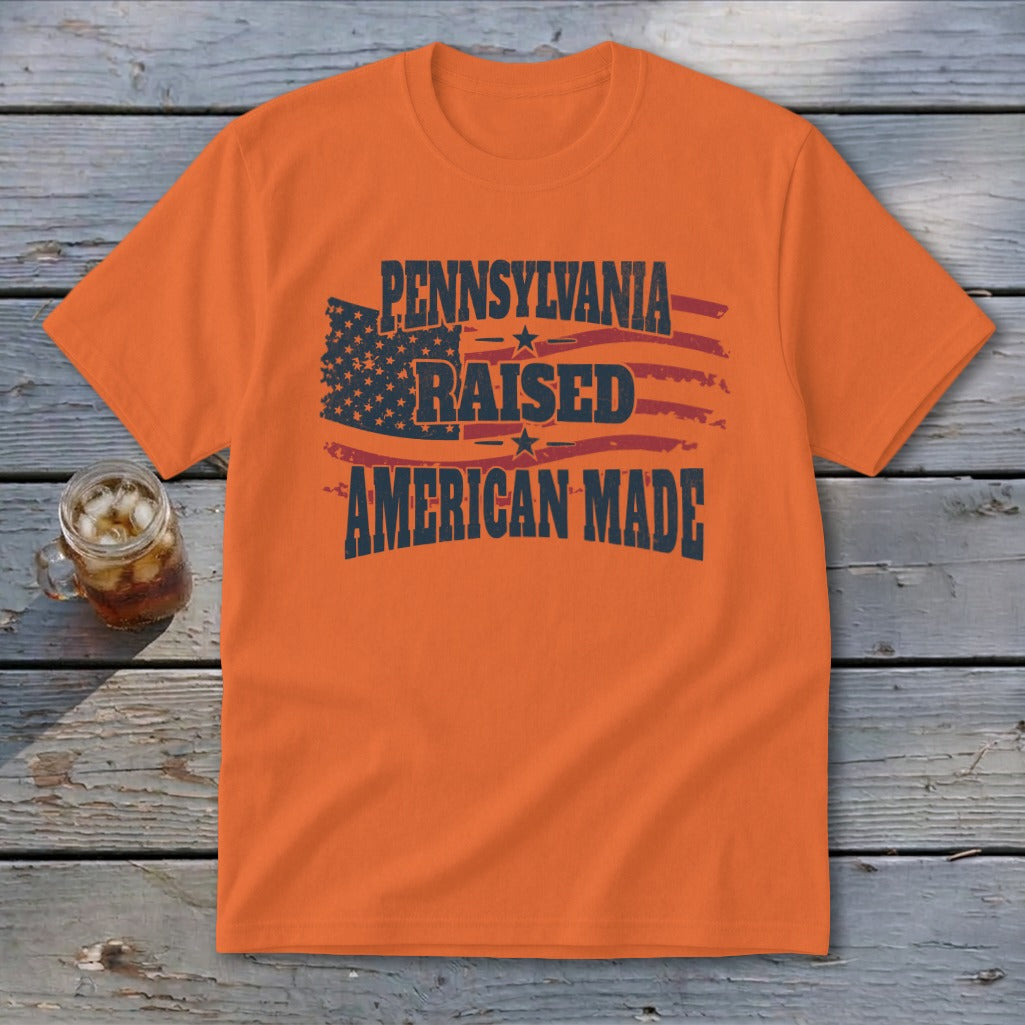 An orange t-shirt featuring the text Pennsylvania Raised American Made and a distressed American flag graphic.