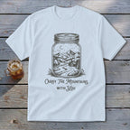 Light blue t-shirt featuring a mason jar illustration filled with a mountain landscape and text Carry The Mountains With You.