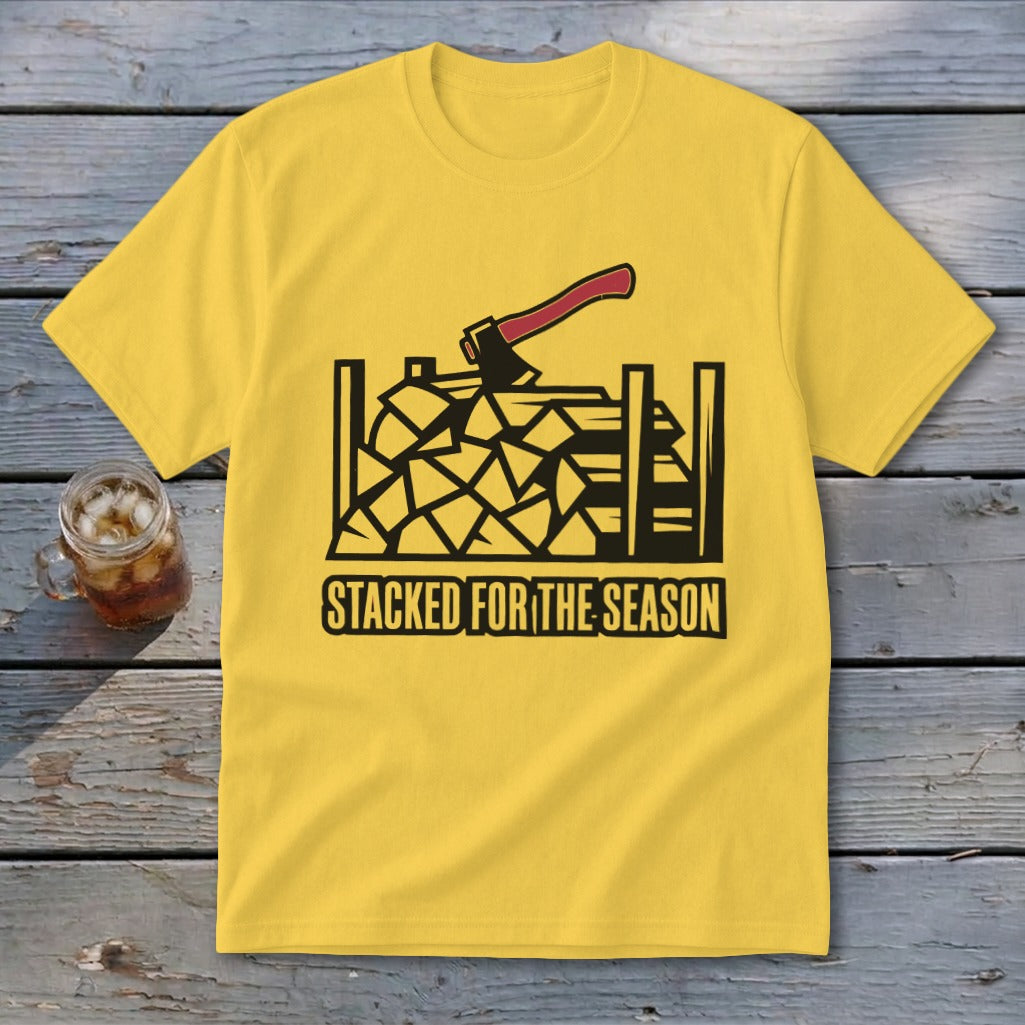 Yellow t-shirt with black graphic of stacked firewood and axe; text "STACKED FOR THE SEASON".
