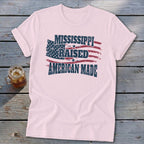 Light pink t-shirt featuring a distressed American flag design with the text Mississippi Raised American Made.