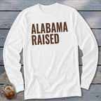 White long-sleeve t-shirt with brown "ALABAMA RAISED" text.