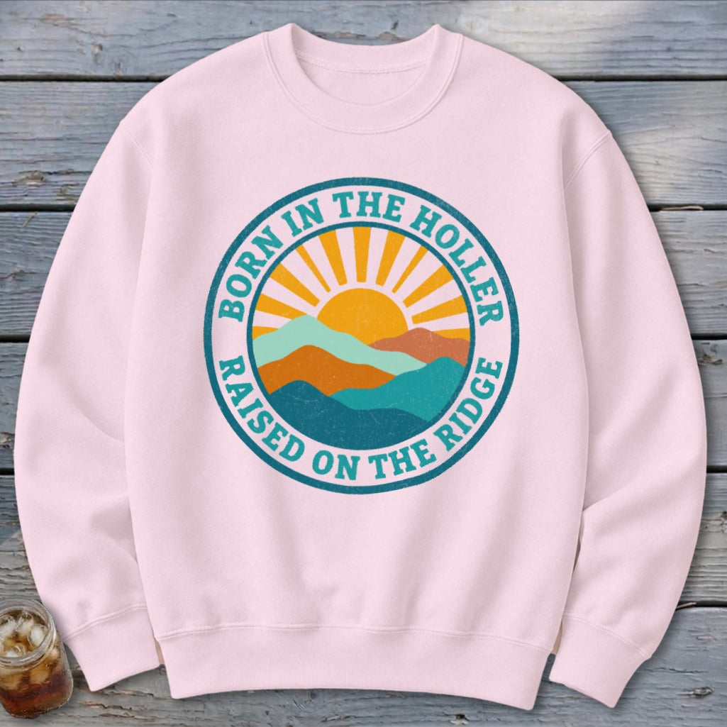Light pink crewneck sweatshirt featuring a circular retro mountain and sun graphic with text.
