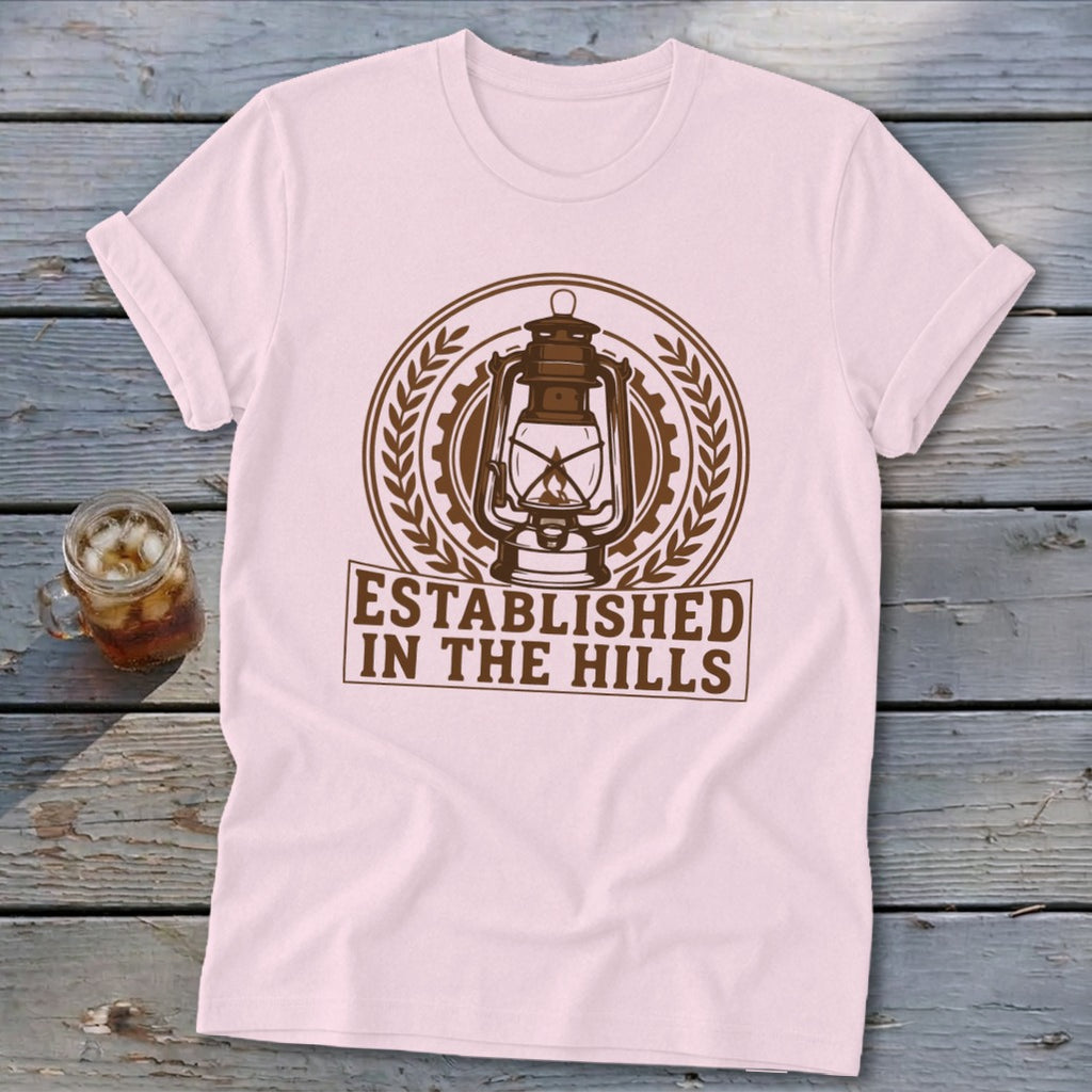 Pink t-shirt with a vintage lantern graphic and text "Established in the Hills."