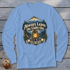 Light blue long sleeve shirt with a graphic featuring a lantern, mountains, and the text "Always Leave the Light On Come On In".