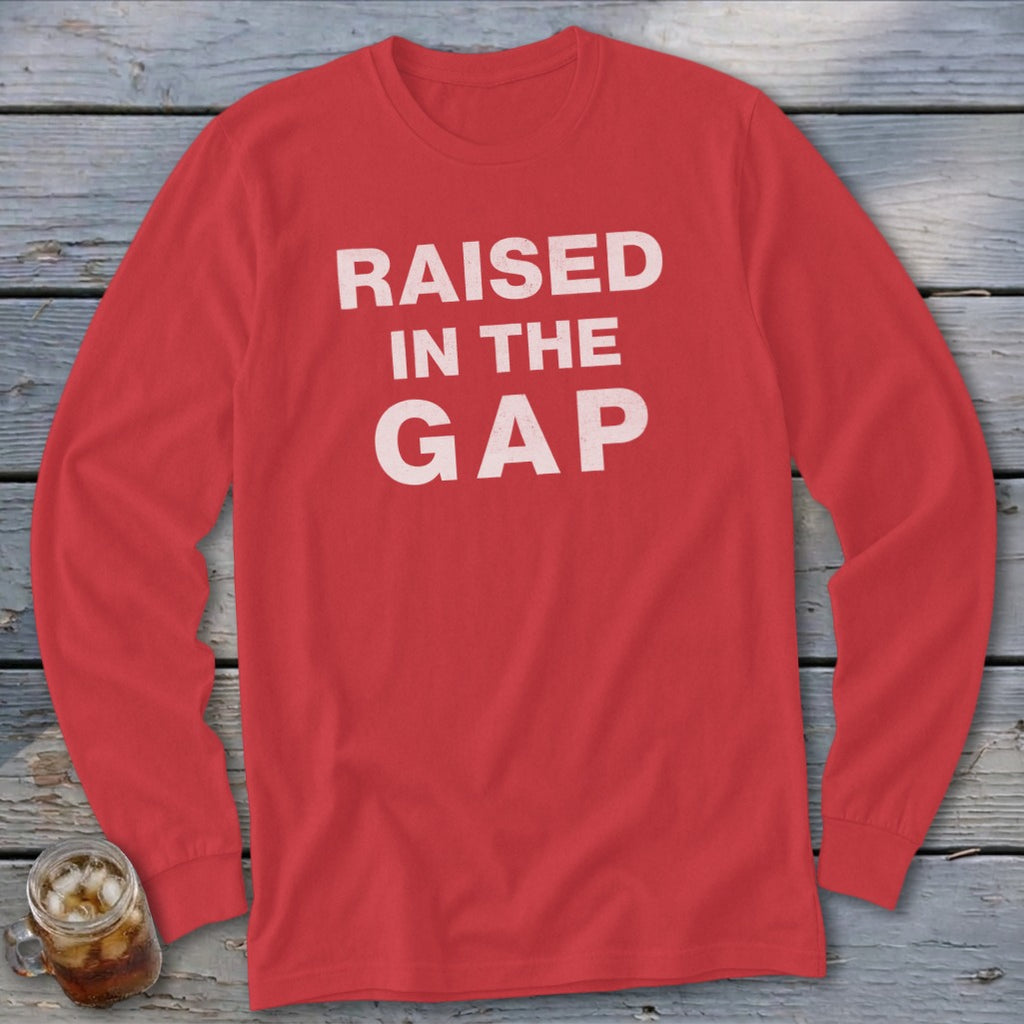 Red long sleeve shirt with white text reading "RAISED IN THE GAP".