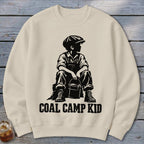 Crewneck sweatshirt with black graphic of a boy in overalls and cap holding a bucket, text reads "Coal Camp Kid."