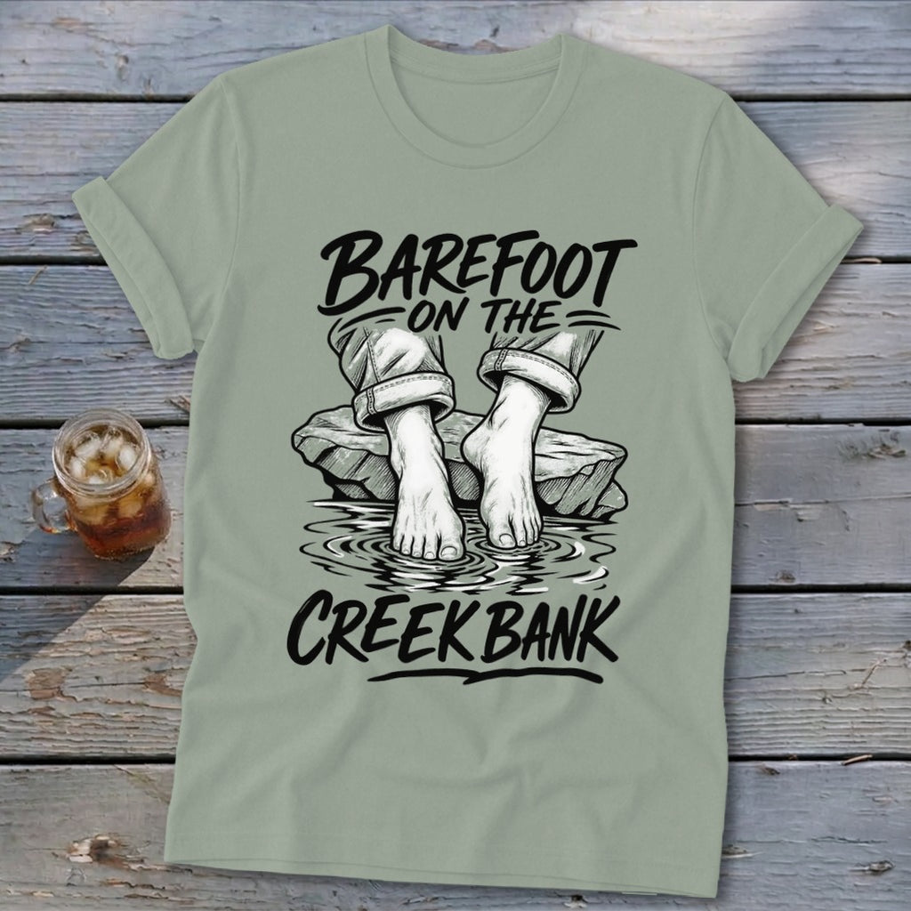 T-shirt with "Barefoot on the Creek Bank" text over bare feet on rocks in water.