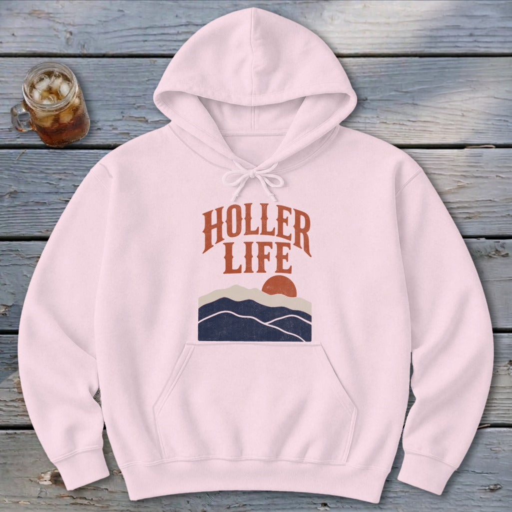 A light pink hoodie with a drawstring hood, front pocket, and a chest graphic featuring mountains, a sun, and the text "HOLLER LIFE".