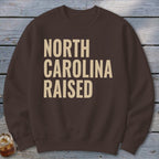 Brown sweatshirt with "North Carolina Raised" printed in tan text.