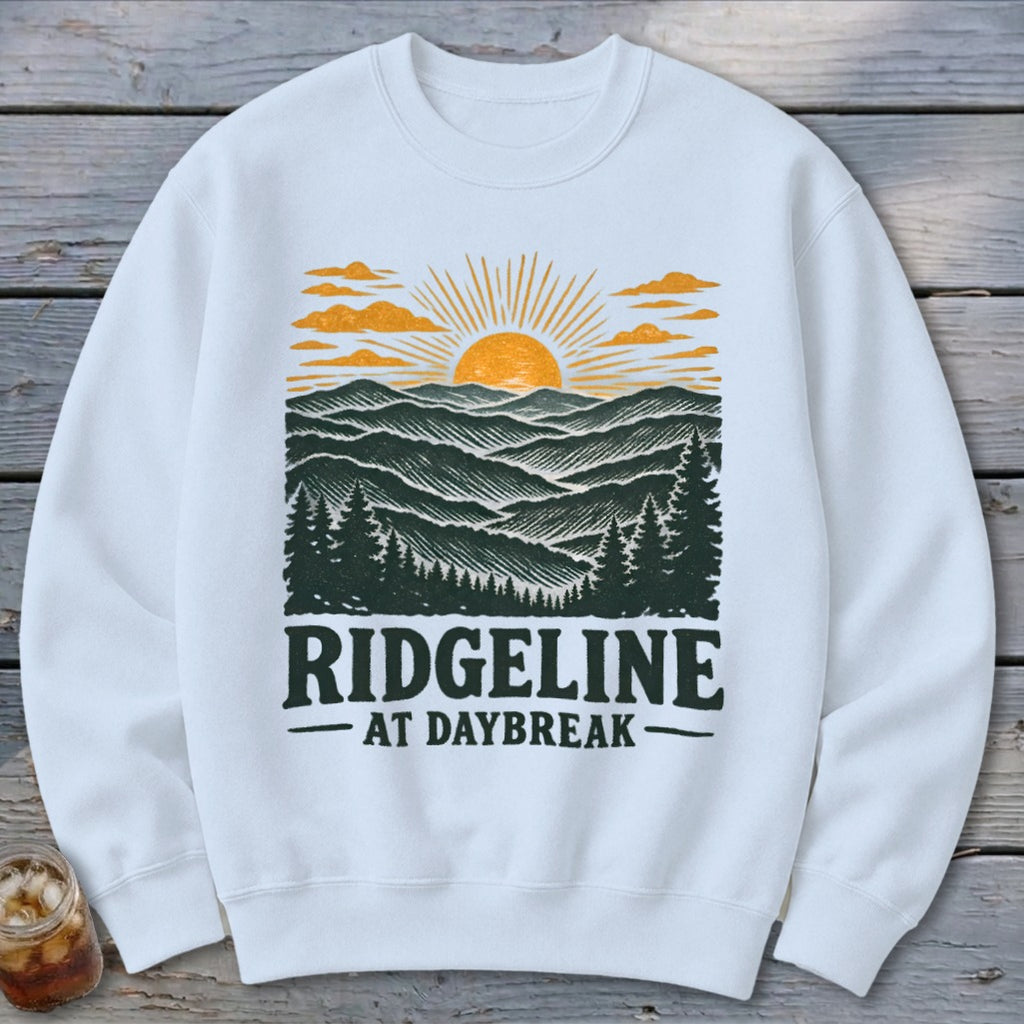 White sweatshirt with a graphic of mountains, trees, and sunrise, reading "RIDGELINE AT DAYBREAK".