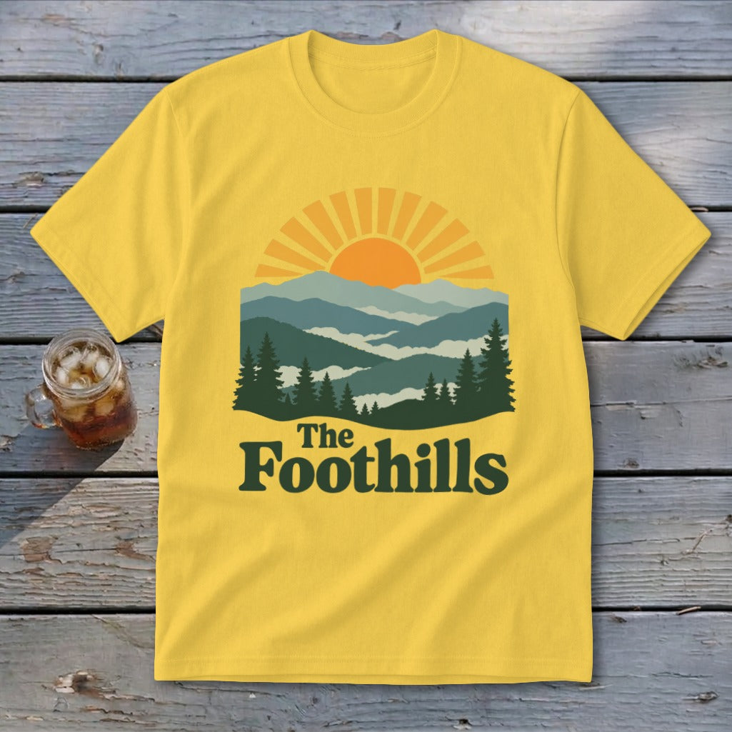 Yellow t-shirt with sun, mountains, trees, and "The Foothills" text.