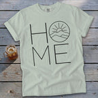 Light green t-shirt with black outline graphic spelling HOME, featuring a mountain sunrise inside the O.
