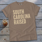 T-shirt with "South Carolina Raised" text in a tan color.