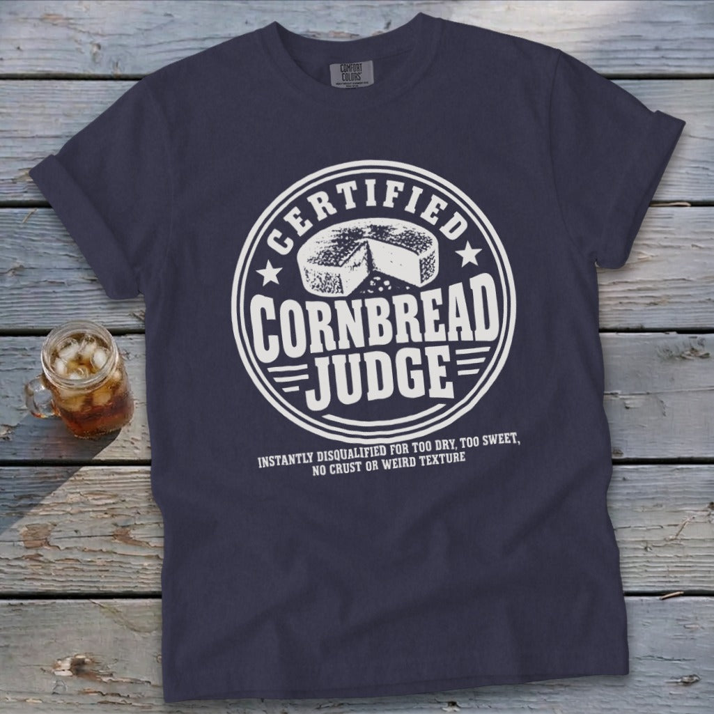 Dark blue crewneck t-shirt with white graphic text reading Certified Cornbread Judge and a cornbread illustration.