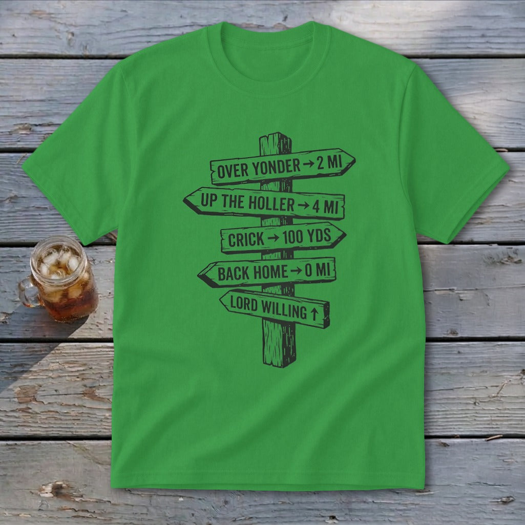 A green short-sleeved t-shirt features a black graphic of a rustic wooden signpost pointing in various directions with humorous text.