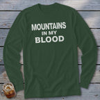 Green long-sleeve shirt with white text "MOUNTAINS IN MY BLOOD".
