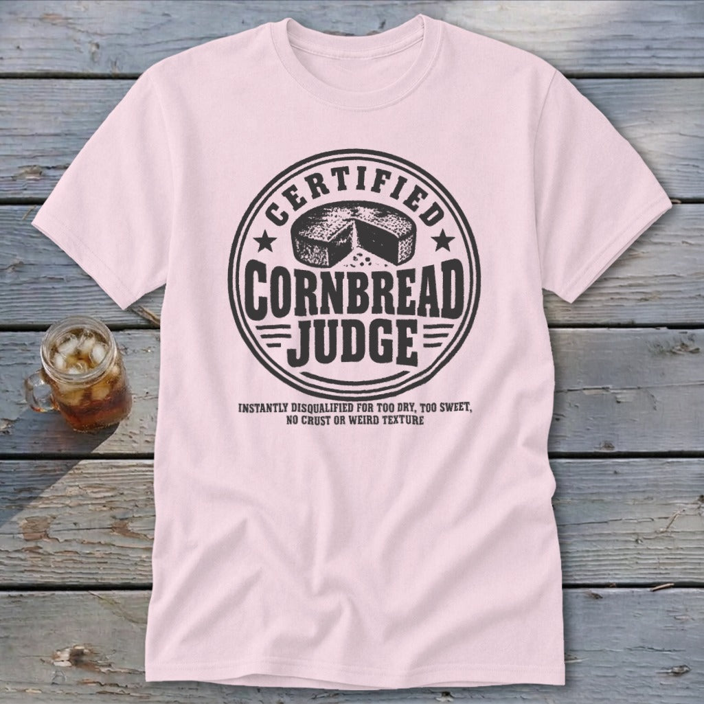 A light pink t-shirt featuring a black graphic with text reading "Certified Cornbread Judge".