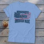Light blue t-shirt displaying a vintage graphic with an American flag and the text Mississippi Raised American Made.