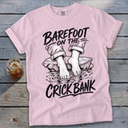 Pink t-shirt with "Barefoot on the Crick Bank" graphic and a glass of iced tea.